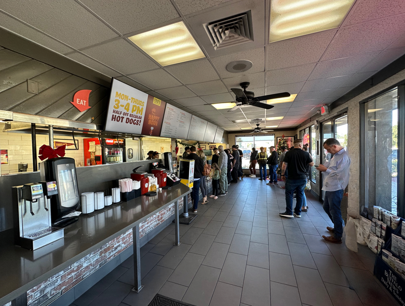 Interior of a fast-casual restaurant with customers queuing at the counter during daytime.