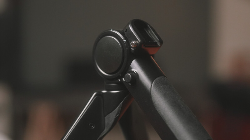 Close-up of a gimbal-mounted camera setup with telephoto lens on a tripod against blurred background.