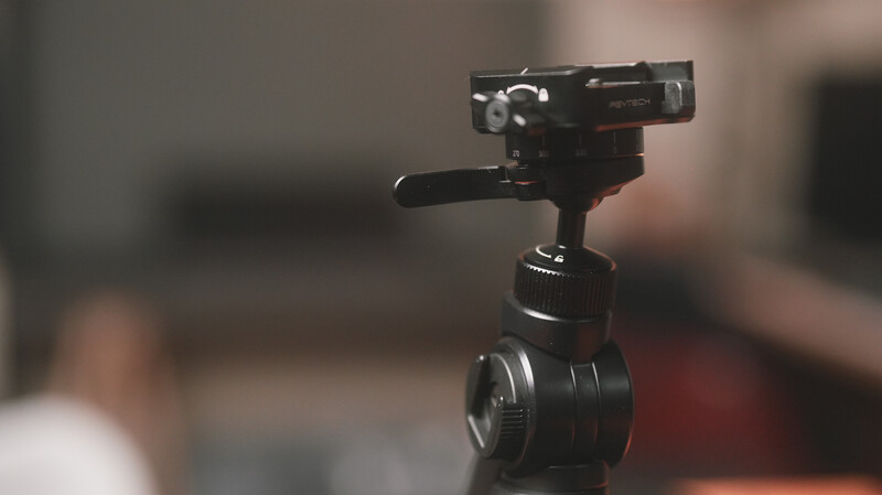 Professional video camera mounted on a ball head tripod with shallow depth of field background.