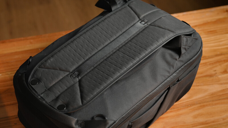 Open black camera backpack displaying internal organization with padded dividers and compartments on wooden surface.