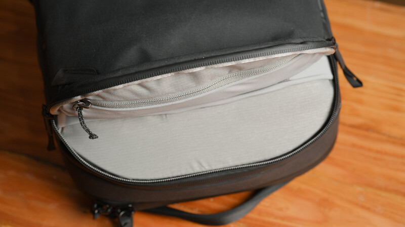 Open camera bag with black exterior and light gray interior compartment on wooden surface.