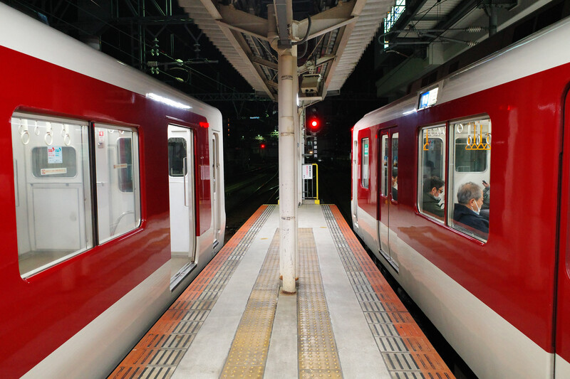 Red and white commuter train stopped at an empty platform, symmetrically framed down the center line.