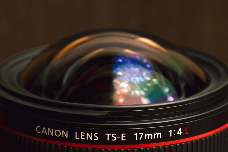 Canon TS-E 17mm f/4L lens with front element visible and colorful lens flare reflections.