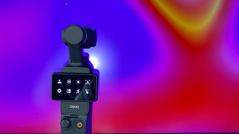 DJI Osmo gimbal with mounted camera against vibrant purple and pink gradient background.