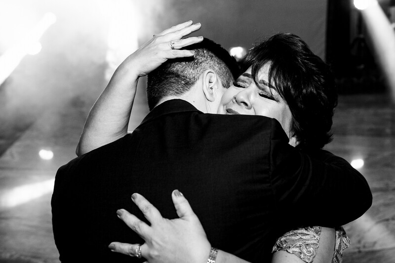 Couple embracing in black and white, with hands visible around shoulders and back.