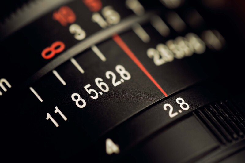 Close-up of a camera lens showing focal length markings and aperture scale with shallow depth of field.