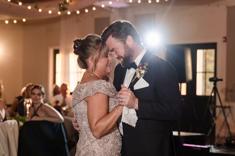 Groom and bride dancing together during first dance at wedding reception with warm ambient lighting.