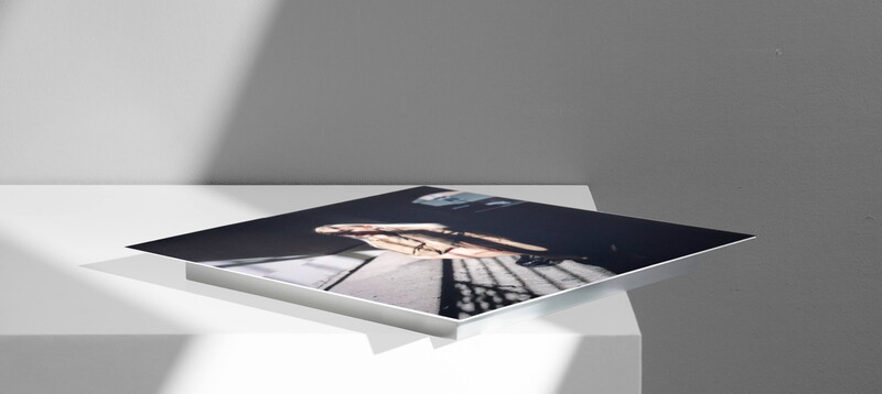 Printed photograph displayed on white surface with dramatic diagonal shadow cast across it.