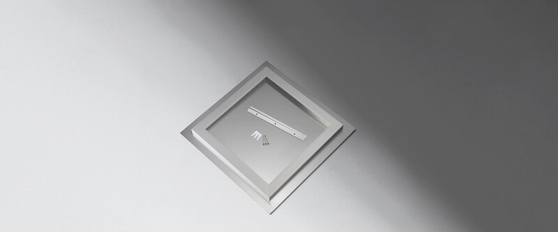 Minimalist product photography of two writing instruments and small fasteners arranged in a recessed square frame against neutral background.