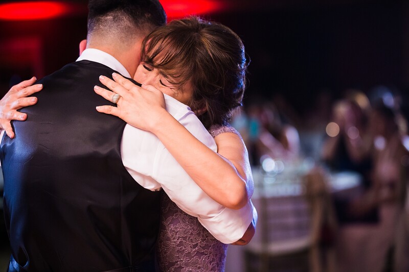 Couple embracing during a formal dance at an indoor event with warm stage lighting.