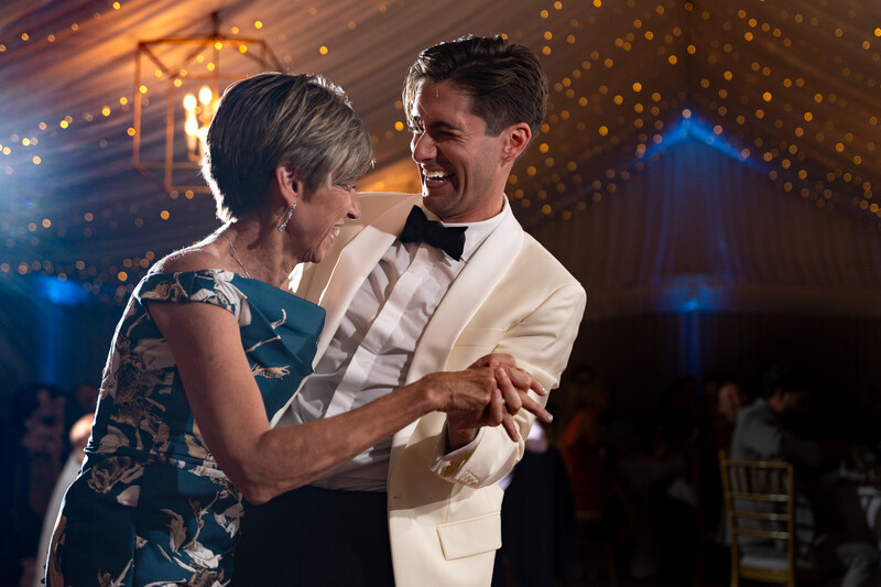 Man and woman dancing at an elegant indoor event with ambient golden and blue lighting.