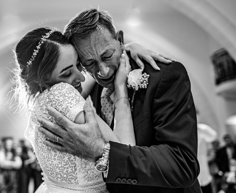 Bride and groom embrace during first dance, captured in black and white photography.