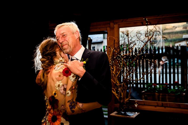 Older man in dark suit dancing with woman in gold patterned dress at indoor event.