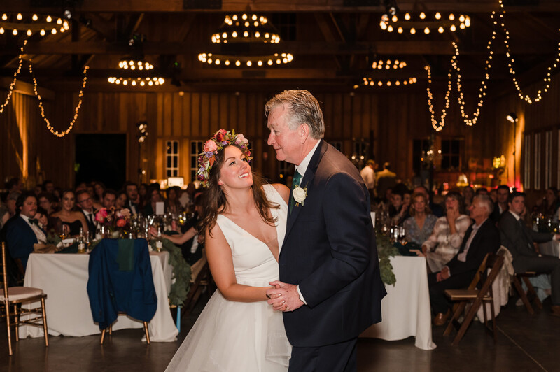 Bride and groom share their first dance at an indoor wedding reception beneath ornate chandeliers.