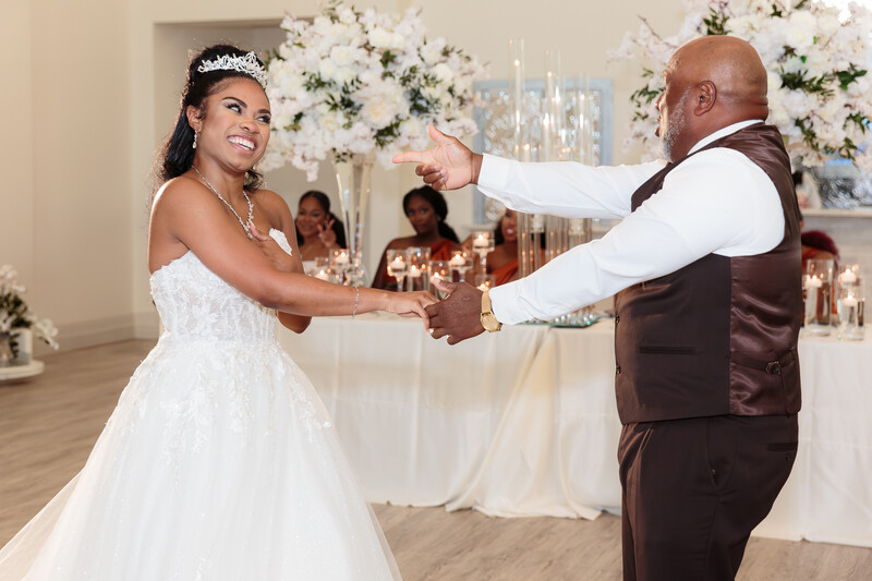 Bride and groom dancing together at their wedding reception, holding hands mid-spin.
