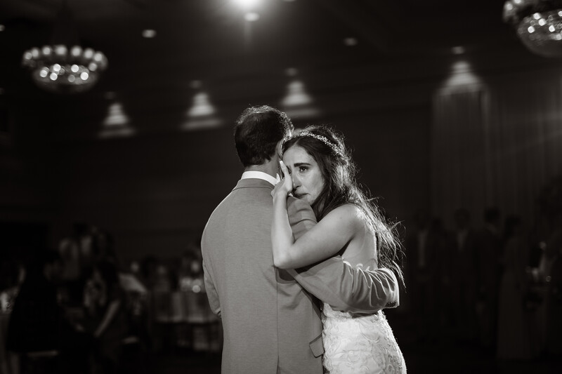 Bride and groom dancing together during their first dance at an indoor wedding reception.