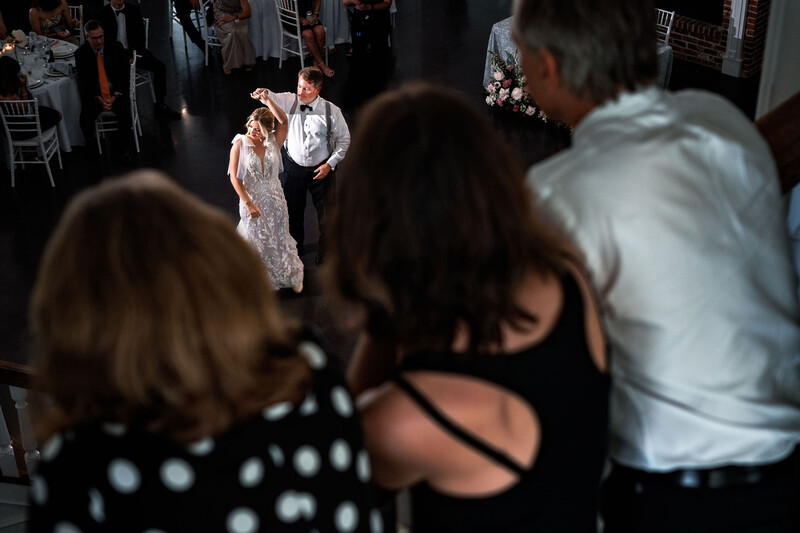 Wedding couple dancing on a lit dance floor while guests watch from the foreground.