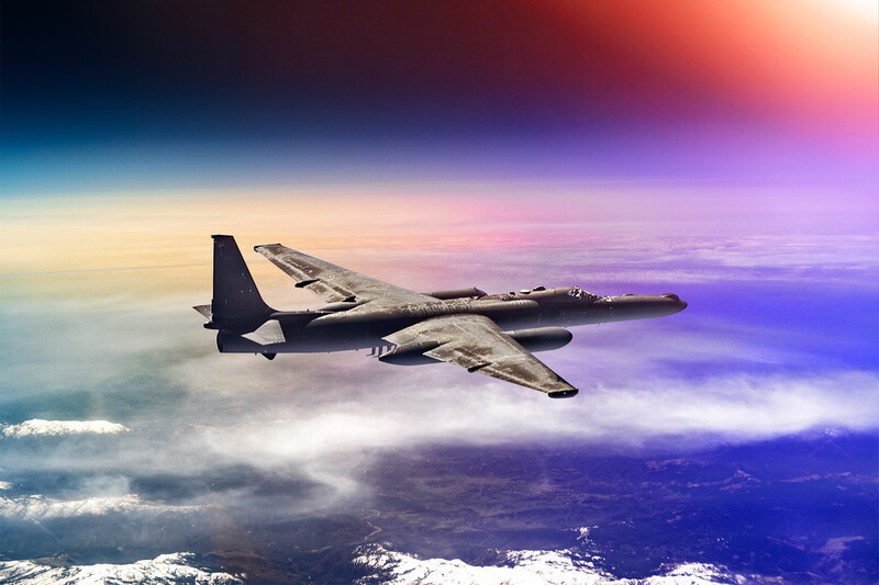 Military transport aircraft flying above clouds during colorful sunset with purple and orange sky.