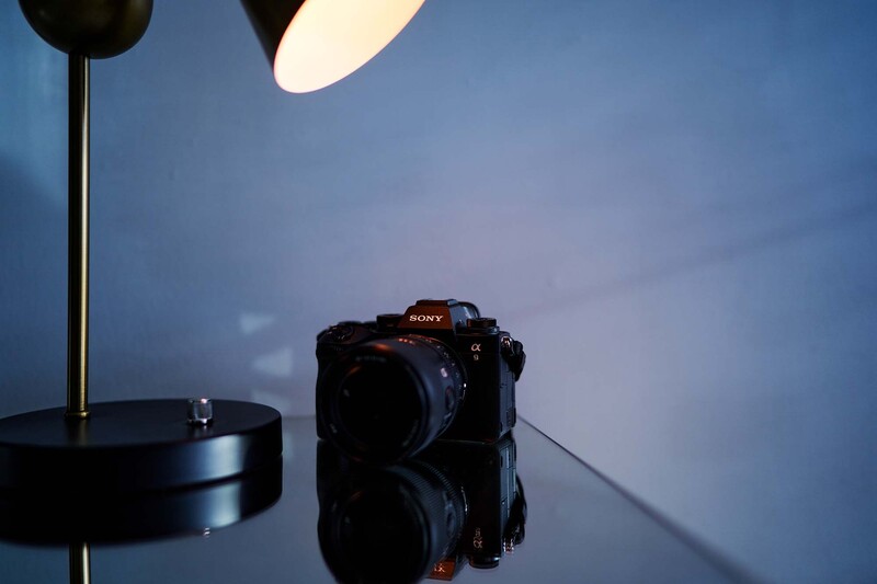 Sony mirrorless camera positioned on reflective surface beneath studio lighting setup.