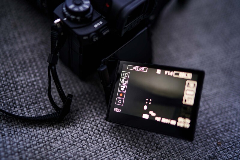 Digital camera and external monitor displaying playback footage on a textured gray surface.