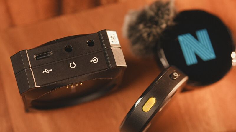 Wireless microphone transmitter and receiver with blue windscreen foam on warm-toned surface.