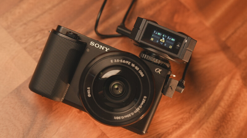 Sony mirrorless camera with attached flash unit on warm fabric background.