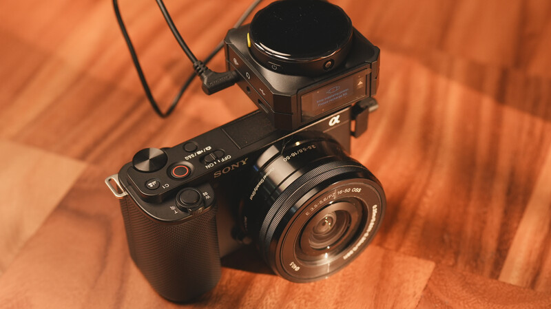 Sony mirrorless camera with wide-angle lens and external flash mounted on top, photographed on wooden surface.