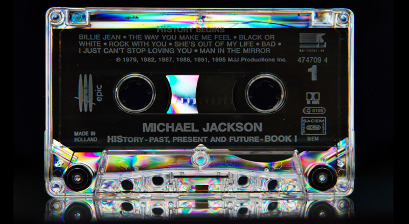Translucent cassette tape with iridescent label showing Michael Jackson album artwork and track listings.