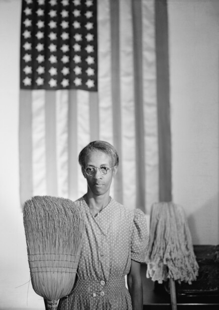 Woman holding woven baskets in front of an American flag backdrop.