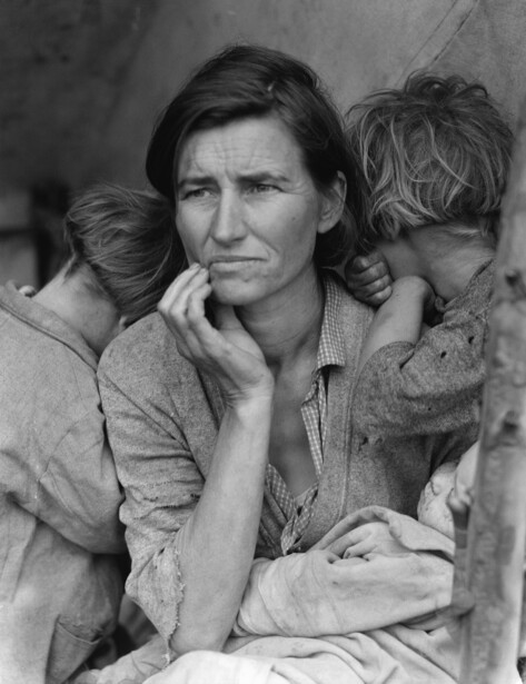 Woman with hand to face holding two children close in a black and white portrait.
