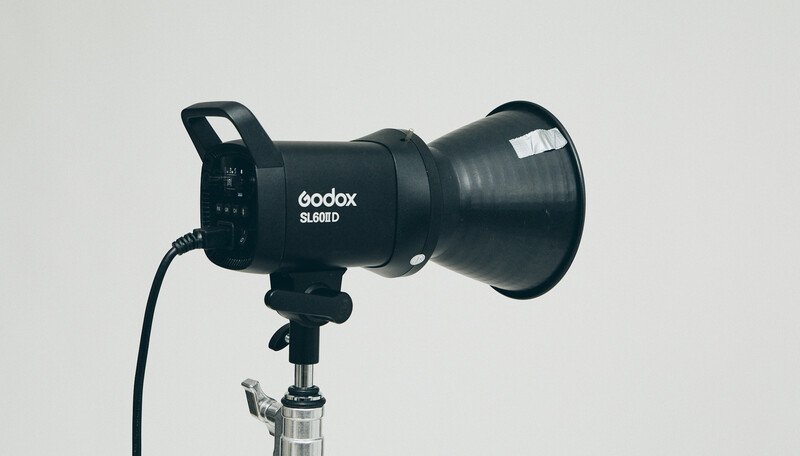Godox SL60D LED monolight mounted on a stand with power cable attached against white background.
