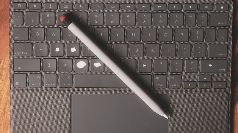 Stylus pen resting diagonally across a laptop keyboard with trackpad visible.