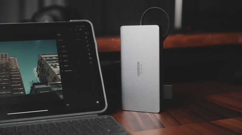 Laptop displaying architectural photography beside an external hard drive on wooden desk.