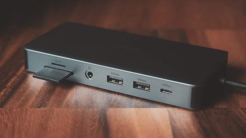 Silver USB hub with multiple ports displayed on a wooden surface.