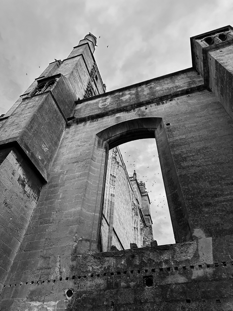 Ruined stone building with large empty window and weathered brick walls shot from below.