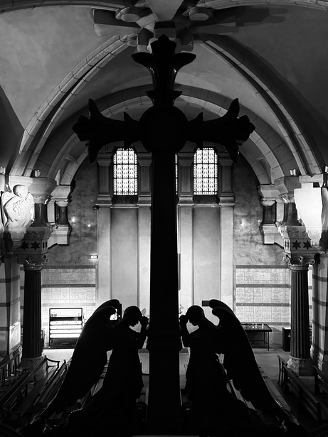 Black silhouette of a large cross with figures kneeling before it in a vaulted church interior.
