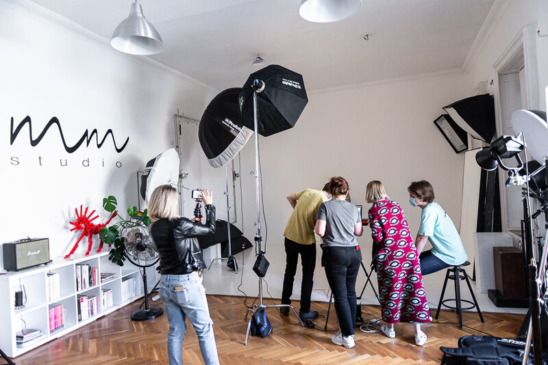 Photography studio session with four people posing while studio lights and umbrellas are set up around them.