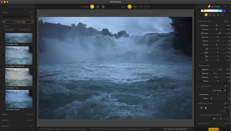 Turbulent ocean waves crashing against rocky coastline at dusk with misty mountains in background.
