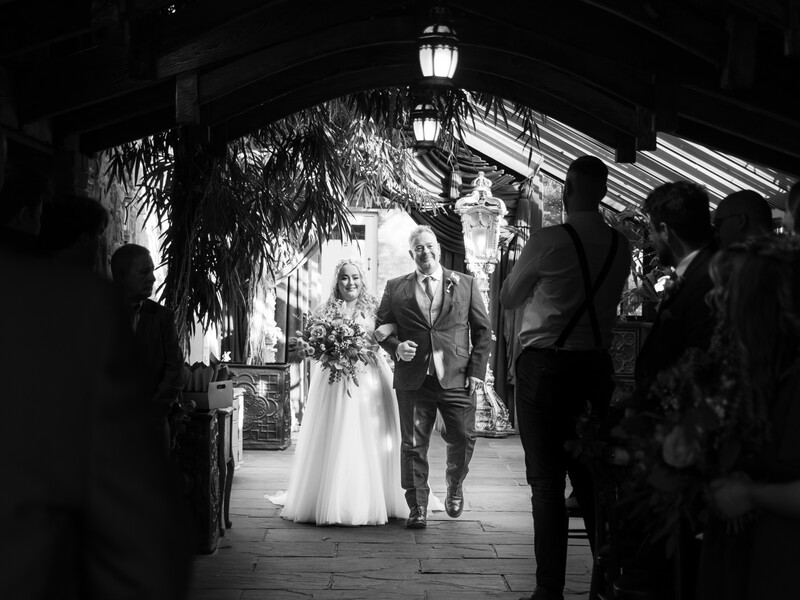 Bride and groom walking together under a covered pavilion during their wedding ceremony.