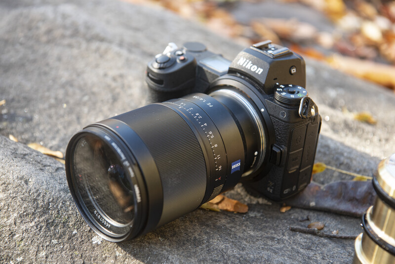 Nikon Z mirrorless camera with Zeiss Milvus lens on concrete surface with fallen leaves.