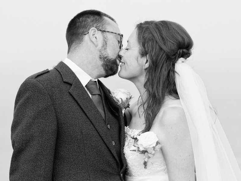 Bride and groom kiss in black and white wedding portrait.