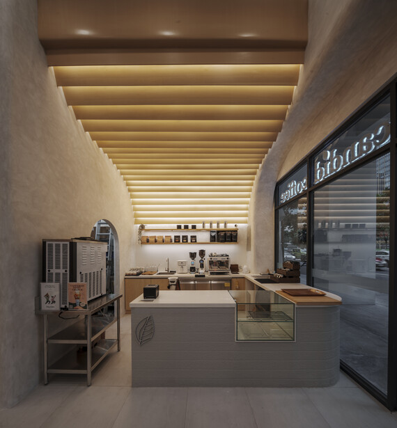 Modern retail interior with warm ceiling lights, minimalist counter, and glass storefront display.