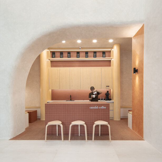 Architectural rendering of a minimalist coffee shop interior with curved walls and warm overhead lighting.