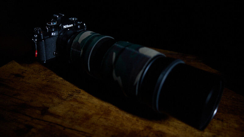 Nikon Z camera with telephoto lens on wooden surface against dark background.