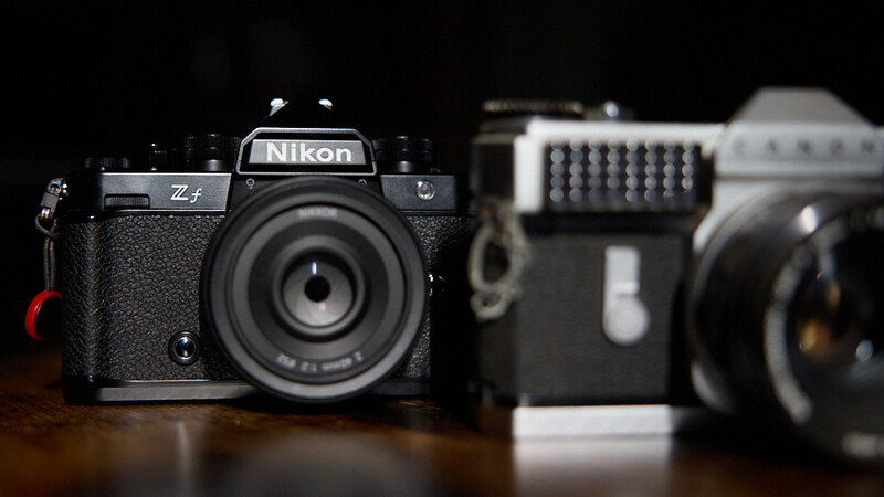 Nikon Zf rangefinder camera in sharp focus with vintage film camera equipment blurred in the background.