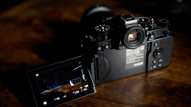 Professional video camera with articulating screen displaying footage on a wooden surface.