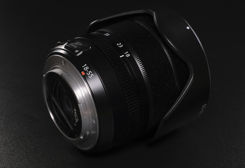 Wide-angle lens with focus ring and depth-of-field markings, photographed against dark background with dramatic lighting.