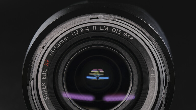 Close-up of a camera lens showing optical elements and lens markings against a dark background.