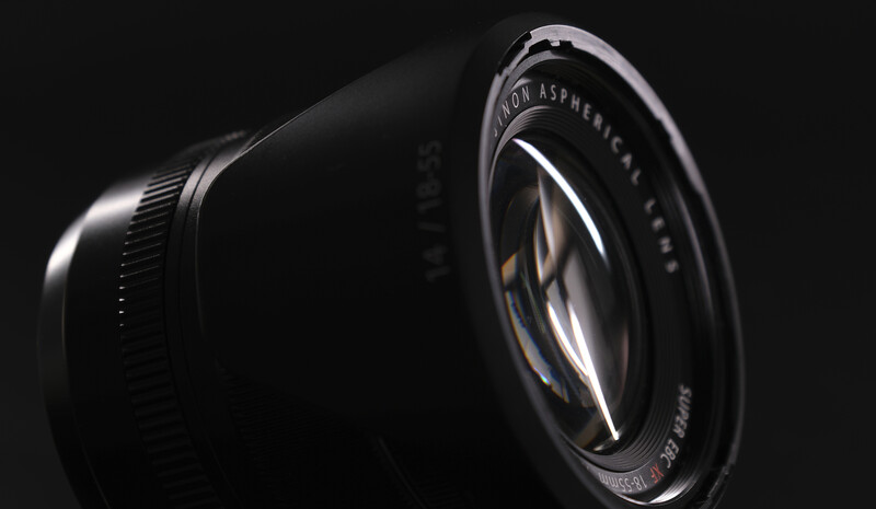 Close-up of a vintage camera lens with glass elements visible through the front element against a dark background.