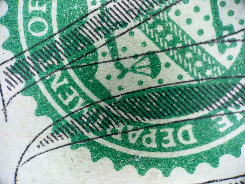 Close-up of overlapping green postage stamps with linear halftone patterns and circular perforations.
